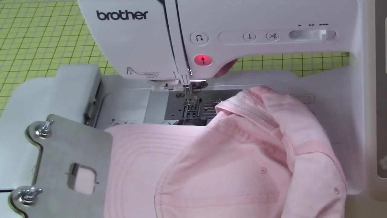 A loaded cap frame being slid onto the Brother SE625 embroidery arm, showing the critical moment where clearance and proper attachment prevent crashes.