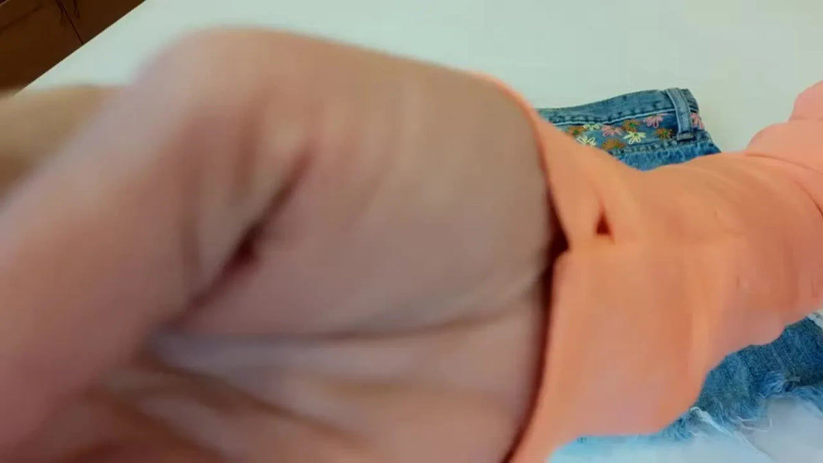 Top-down view of distressed denim shorts before embroidery.