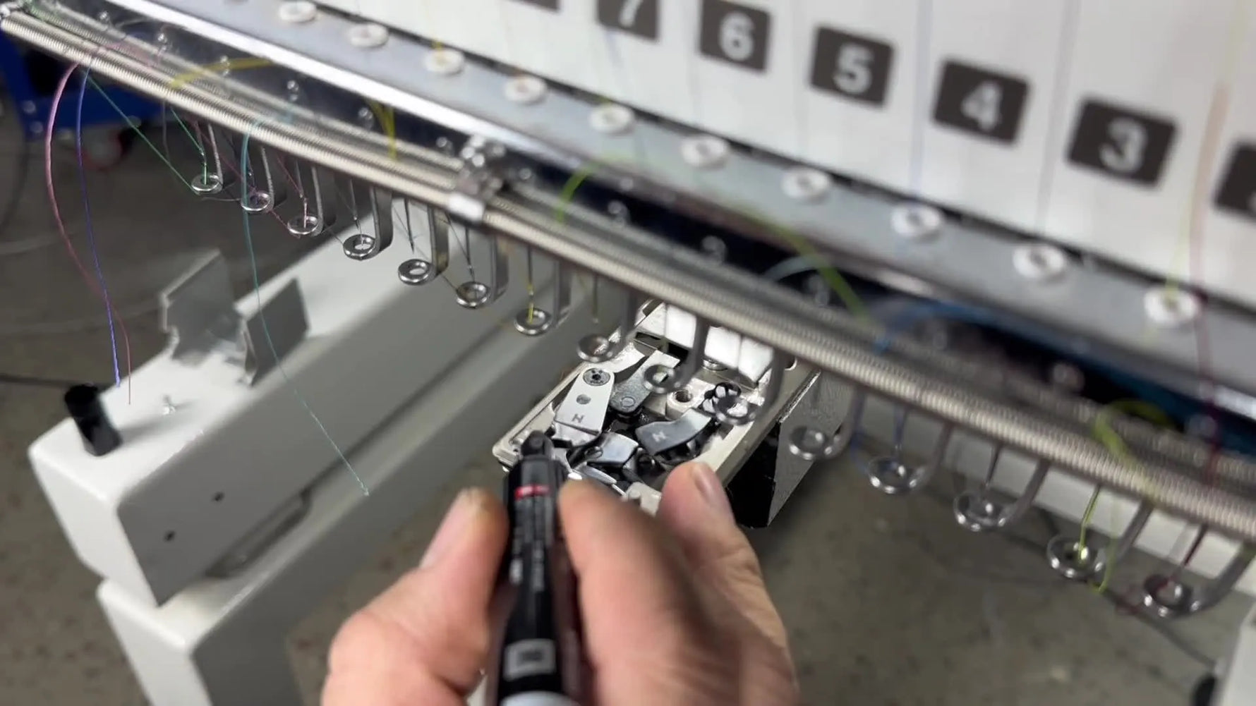 A technician colors the trimmer blade with a black marker to verify knife-to-knife friction before adjusting the trimmer collar screws.