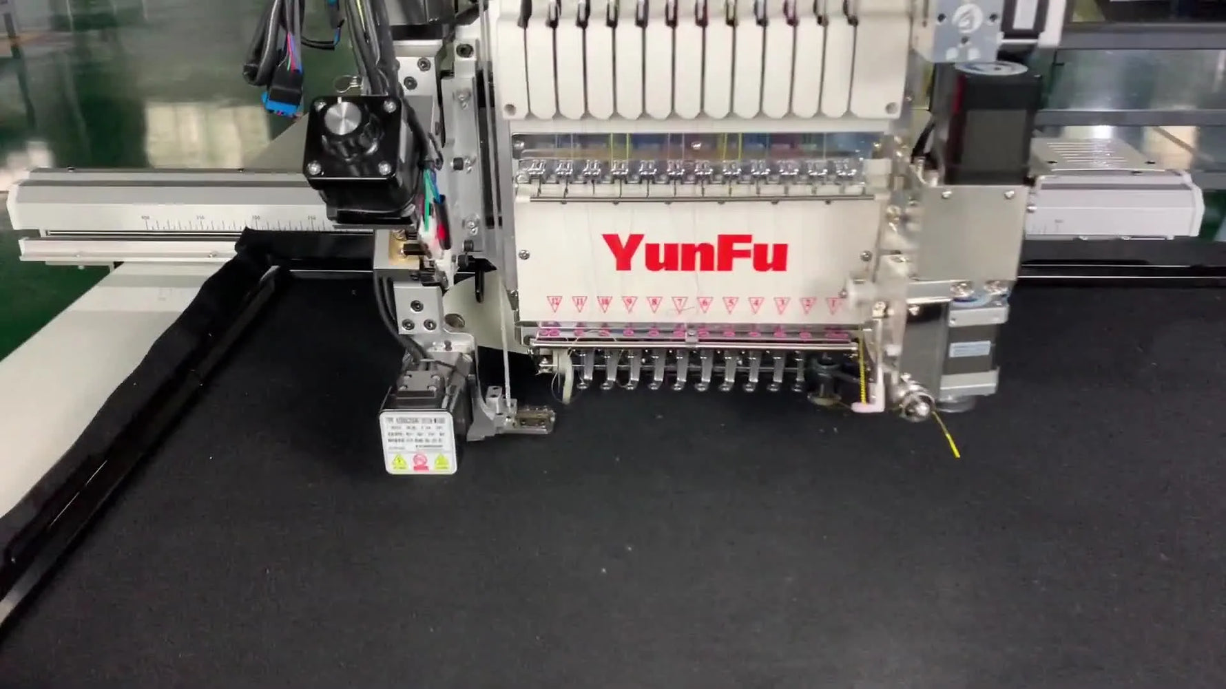 Extreme close-up of the YunFu bead device feeding white beads as the needle secures them onto black fabric.